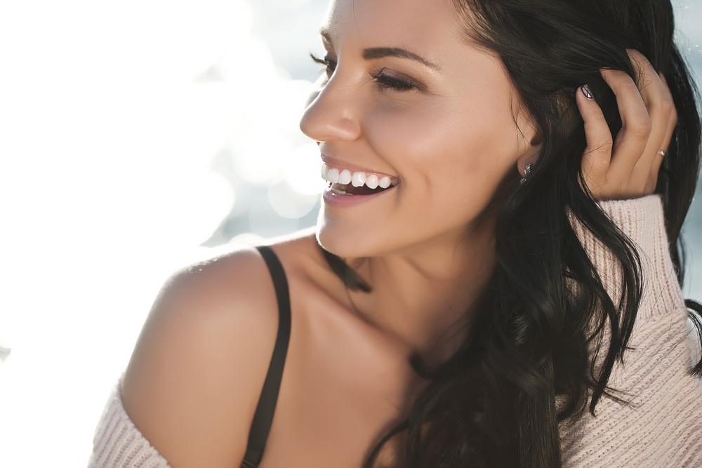 Beautiful woman with dark hair smiling from a profile view.