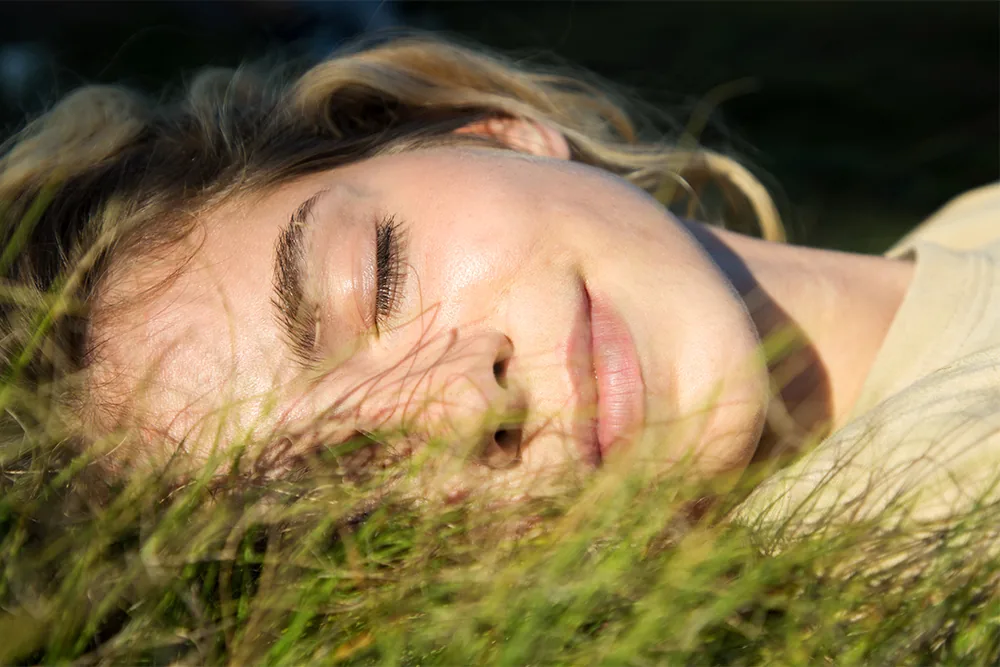 Peaceful woman with eyes closed laying in grass